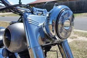 Close-up of a vintage motorcycle's shiny headlight and front fork.