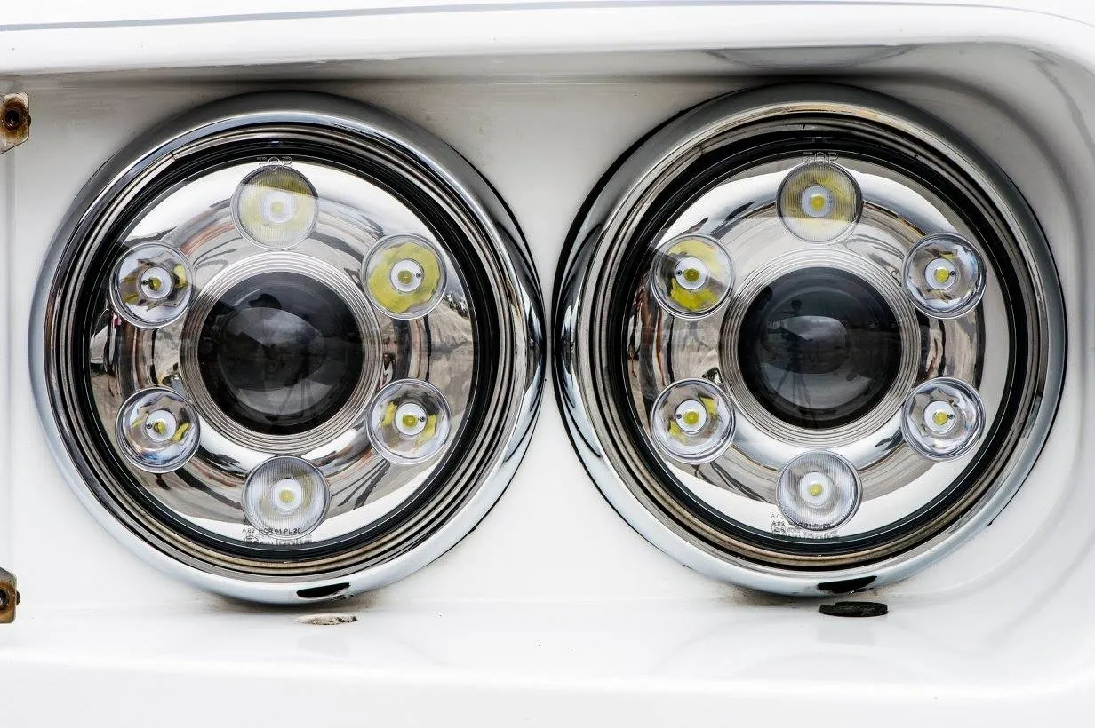 Close-up of two modern LED car headlights with chrome surrounds.