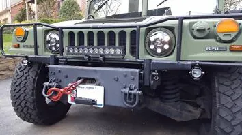 Close-up of a green off-road vehicle front with winch and rugged bumper.