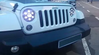 Front view of a white Jeep with LED headlights on.