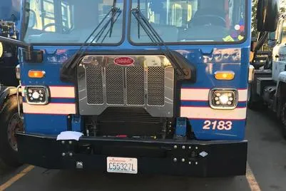 Front view of a blue Peterbilt truck with a prominent grille and license plate.