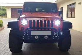 Front view of a black Jeep with bright LED headlights on.