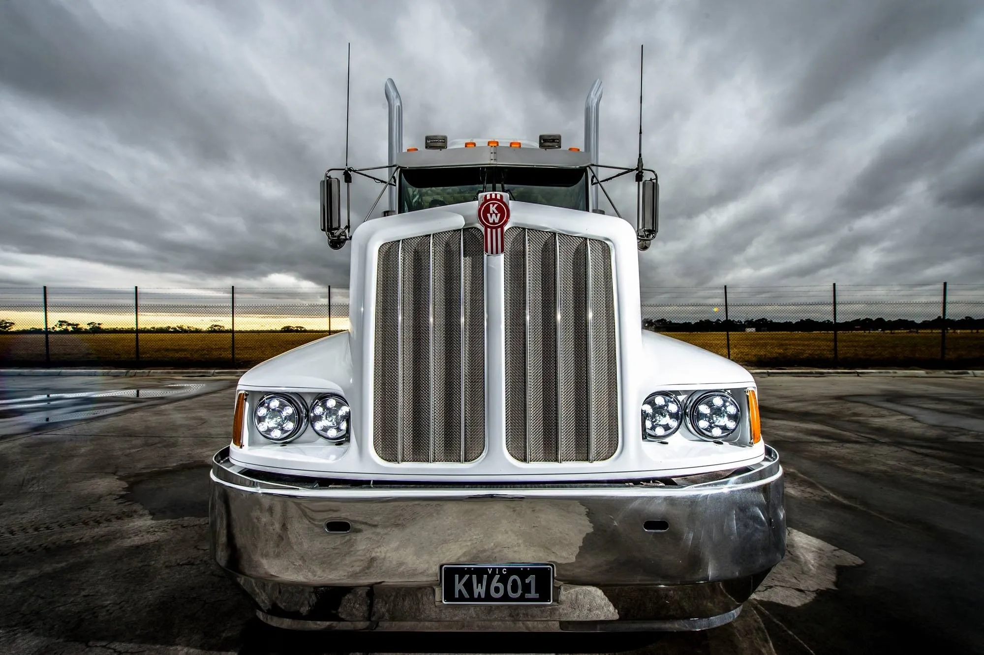 Front view of a large Kenworth truck under a cloudy sky.