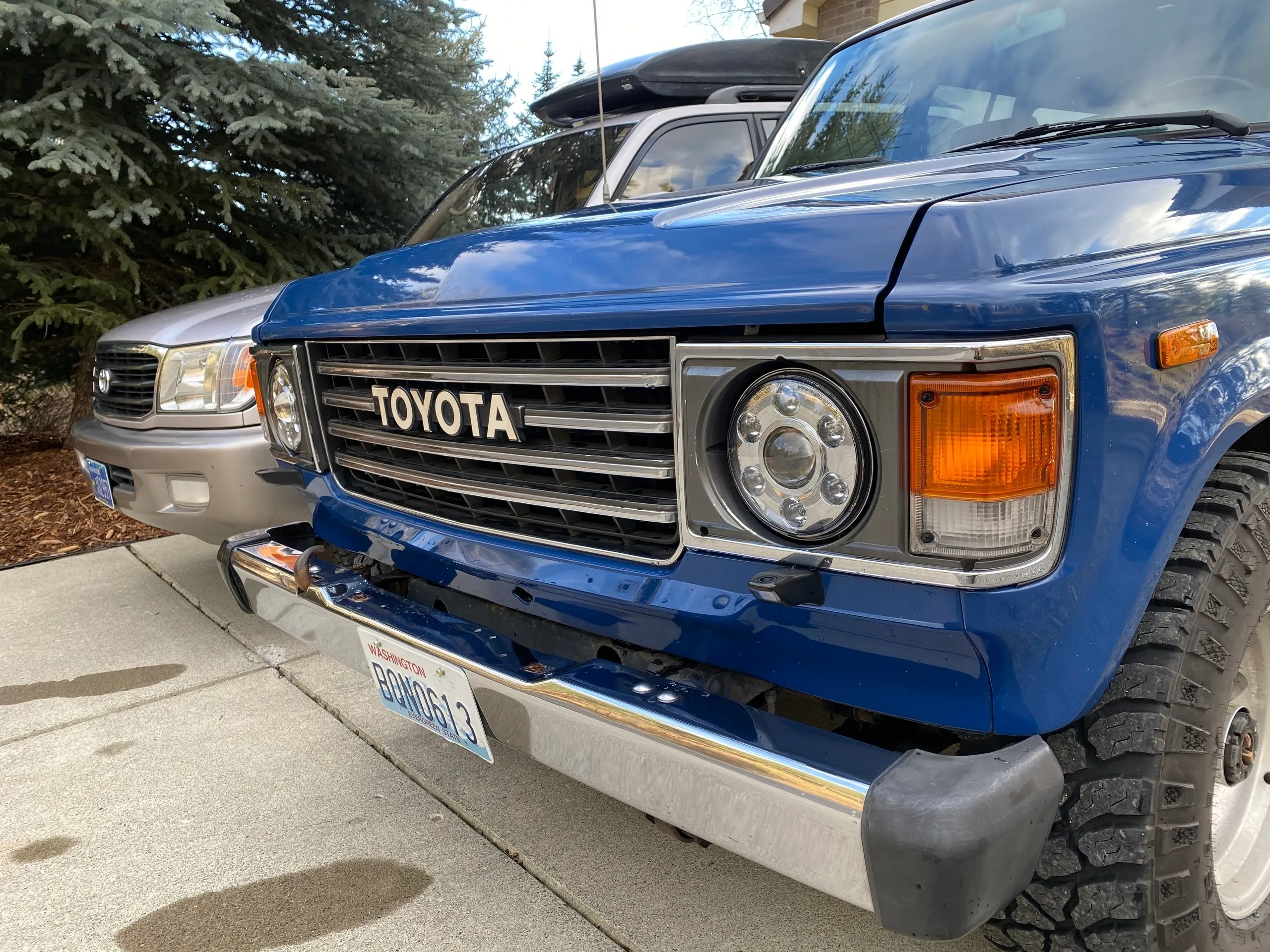 Close-up of a classic blue Toyota vehicle's front grille and headlight.